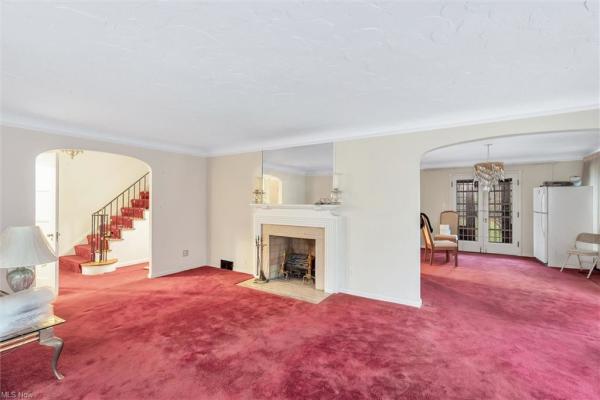 Living room with fireplace, wine-colored carpeting, and floor-length windows in Cleveland, Ohio house for sale, listed by Will Davis, Ohio probate specialist and realtor