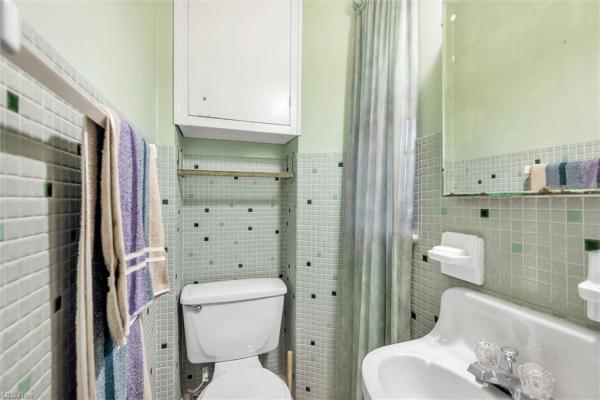 Bathroom with green colored walls and different shades of green colored wall tile in Cleveland, Ohio house for sale, listed by Will Davis, Ohio probate specialist and realtor