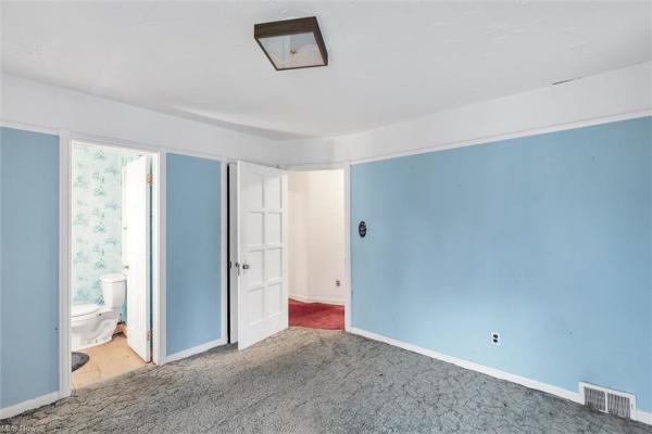 Bedroom with light blue walls, gray blue carpet, shot leading to bathroom and hallway in Cleveland, Ohio house for sale, listed by Will Davis, Ohio probate specialist and realtor