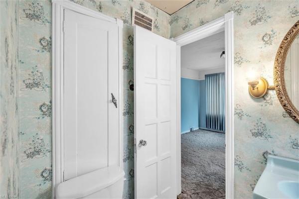 Bathroom with vintage white cabinetry and vintage light blue wallpaper in Cleveland, Ohio house for sale, listed by Will Davis, Ohio probate specialist and realtor