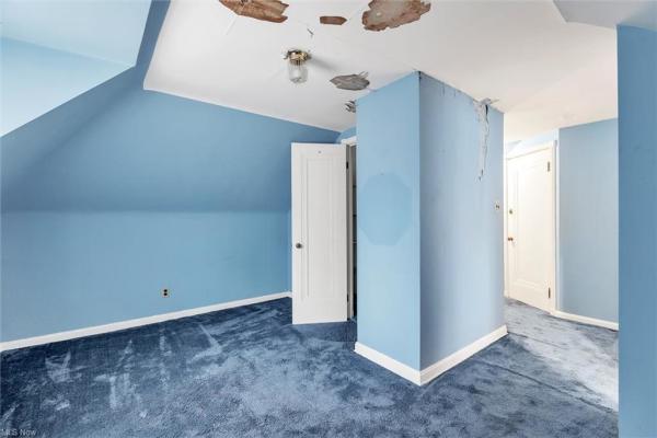 Bedroom with light blue carpeting, light blue walls, cracks in ceiling and one wall, shot facing closet door and hallway in Cleveland, Ohio house for sale, listed by Will Davis, Ohio probate specialist and realtor